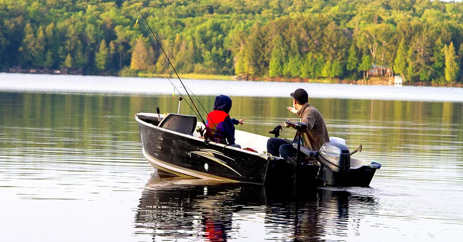 Father and son fishing on lake in boat